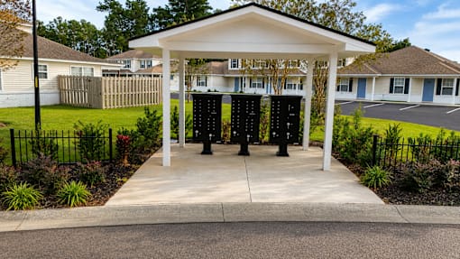 A white pavilion with a black pole in front of a building.
