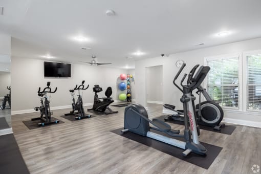 a gym with treadmills and other exercise equipment and a tv
