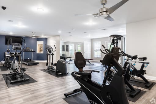 a gym with various exercise machines and a ceiling fan