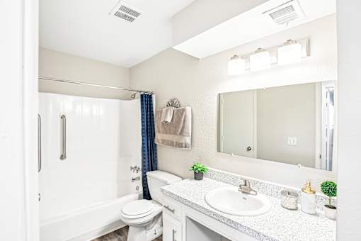 A white bathroom with a toilet, sink, and mirror.
