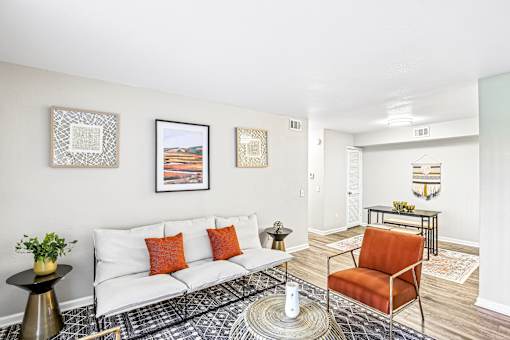A living room with a white couch, a black and white patterned rug, and a red chair.