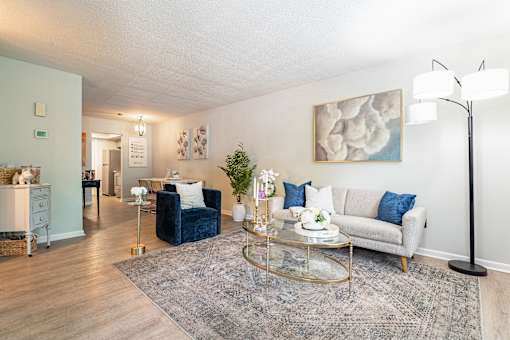 A living room with a blue sofa and a glass coffee table.