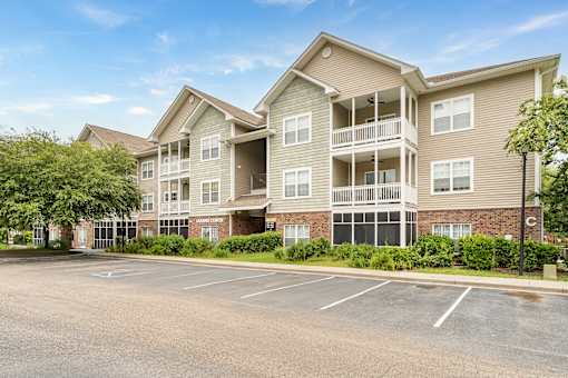 A large apartment complex with a parking lot in front.