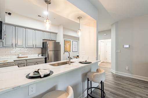 A modern kitchen with a bar stool and a fridge.