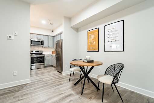 A kitchen with a table and chairs in the foreground and a fridge in the background.