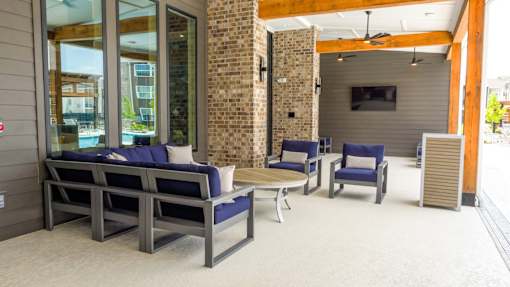 A patio with a couch, chairs, and a television.