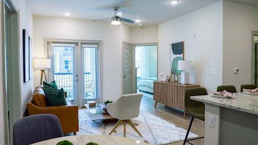 A living room with a white ceiling fan and a white rug on the floor.
