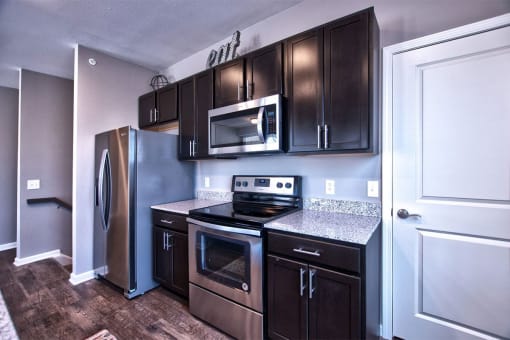 a kitchen with dark cabinets and stainless steel appliances at Park 33, Indiana, 46526