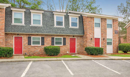 a brick apartment building with red doors and a parking lot at Savan Pointe Townhomes East and West, Savannah Georgia