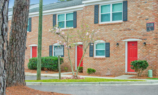 a brick building with red doors and green shuttered windows at Savan Pointe Townhomes East and West, Savannah Georgia