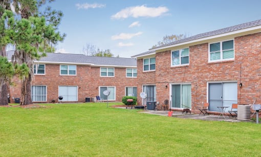 a brick apartment building with a green lawn and trees at Savan Pointe Townhomes East and West, Savannah, GA