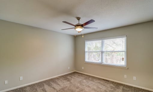 an empty bedroom with a ceiling fan and a window at Savan Pointe Townhomes East and West, Savannah, GA 31406