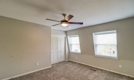 an empty living room with a ceiling fan and two windows at Savan Pointe Townhomes East and West, Savannah, GA