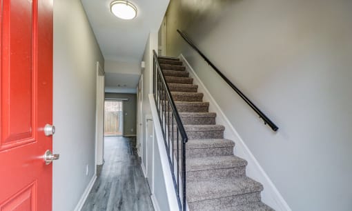 the stairway up to the second floor of a house with a red door at Savan Pointe Townhomes East and West, Savannah, GA