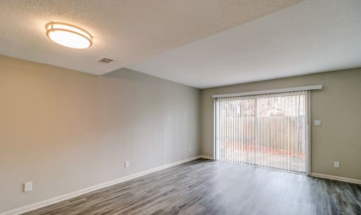 an empty living room with a large window and a sliding glass door at Savan Pointe Townhomes East and West, Savannah
