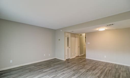 an empty living room with wood flooring and white walls at Savan Pointe Townhomes East and West, Savannah, GA 31406