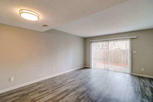 an empty living room with a sliding glass door and a window at Savan Pointe Townhomes East and West, Savannah, GA 31406