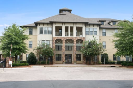 an apartment building with a driveway and trees in front of it