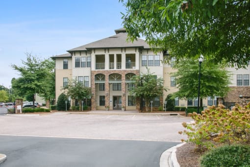 a large building with a driveway and trees in front of it