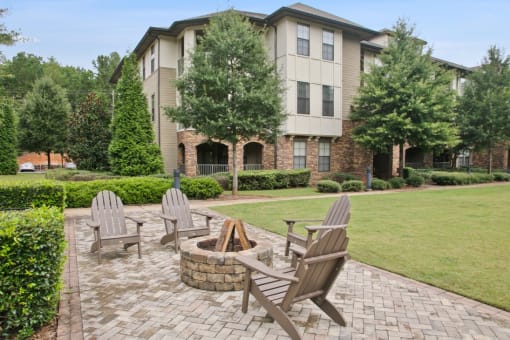 an outdoor patio with chairs and a fire pit in front of an apartment building