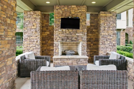a patio with wicker furniture and a stone fireplace