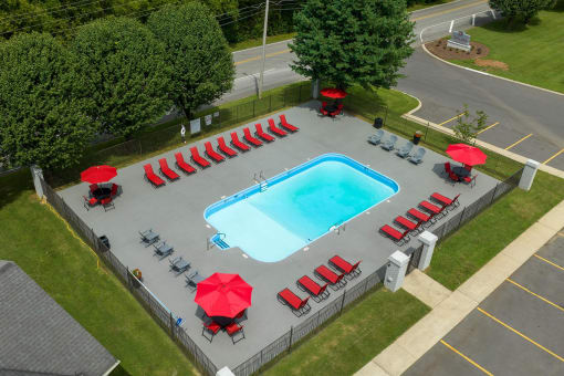 a swimming pool with red umbrellas and chairs around it at The Dylan, Murfreesboro Tennessee