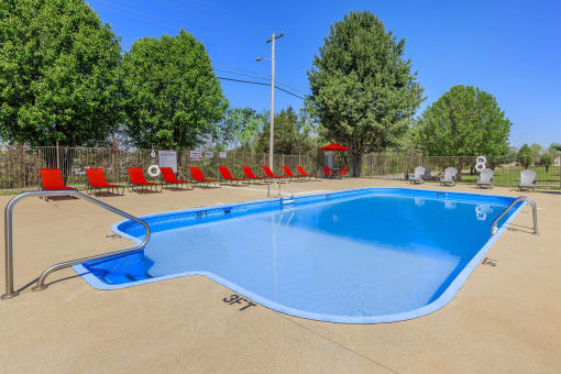 a swimming pool with red chairs around it and trees at The Dylan, Murfreesboro, 37129