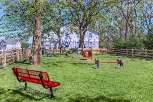 a park with a red bench and kids playing in the grass at The Dylan, Murfreesboro, TN 37129