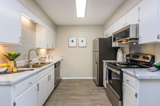 a kitchen with stainless steel appliances and white cabinets at The Dylan, Tennessee 