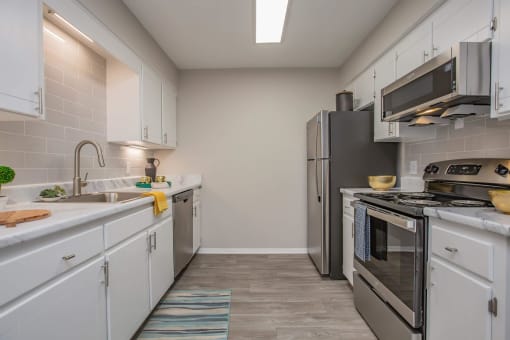 a kitchen with stainless steel appliances and white cabinets at The Dylan, Tennessee