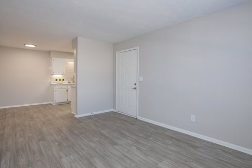 an empty living room and kitchen with wood flooring and a white door at The Dylan, Murfreesboro Tennessee