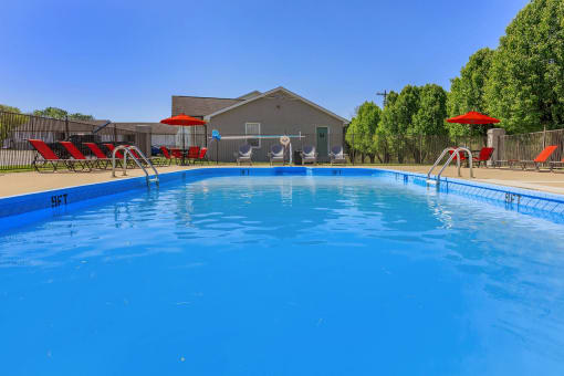 a large pool with chairs and umbrellas next to a house at The Dylan, Murfreesboro, TN 