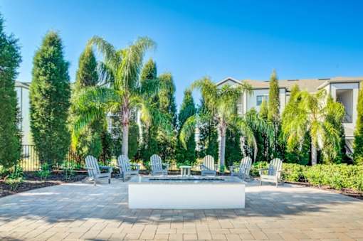 A patio with a white table surrounded by trees and chairs.at Century Ariva, Florida  