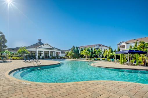 A large swimming pool surrounded by a brick patio and a house in the background.at Century Ariva, Lakeland, Florida  