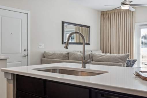 A modern kitchen with a white countertop and a stainless steel sink.at Century Hampton Roads, Suffolk Virginia  