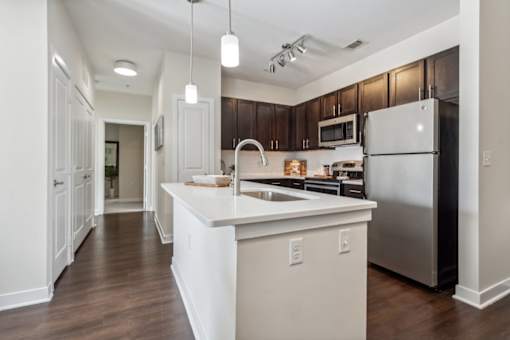 A modern kitchen with a white island and stainless steel appliances.at Century Hampton Roads, Suffolk  