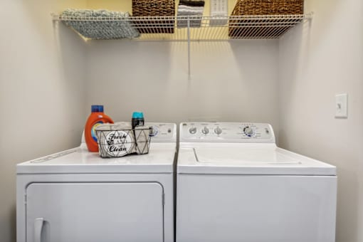 A white washer and dryer with a basket and bottles on top.at Century Hampton Roads, Virginia  