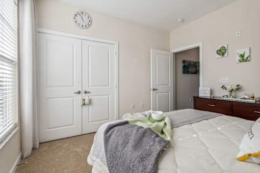 A bedroom with a bed, dresser, and two doors.at Century Hampton Roads, Virginia  