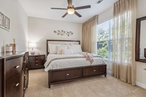 A bedroom with a large bed, a dresser, and a ceiling fan.at Century Hampton Roads, Suffolk, VA 23435  