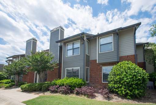 A grey house with a red brick base and a grey roof at Ridge Crossings Apartments, Alabama