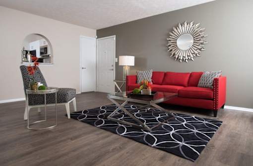 A living room with a red couch, a chair, and a coffee table at Ridge Crossings Apartments, Hoover, AL
