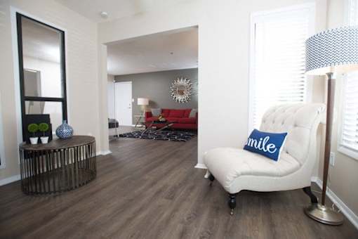 A living room with a white chair and a blue pillow that says smile at Ridge Crossings Apartments, Hoover, AL 35244