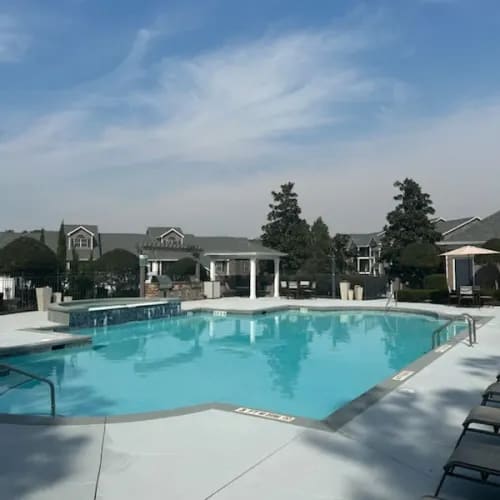 A large swimming pool surrounded by lounge chairs and umbrellas.