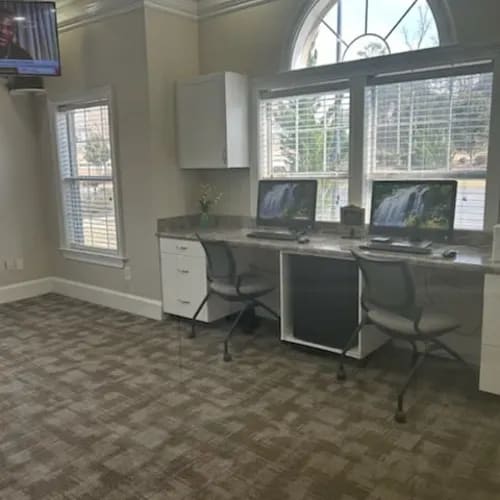 A room with a desk and chairs with a window in the background.