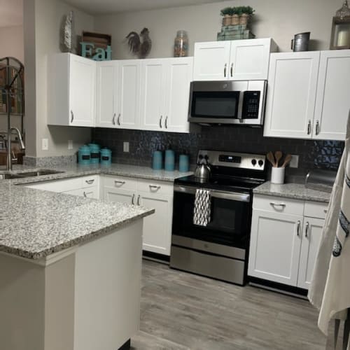 A kitchen with white cabinets and a granite countertop.