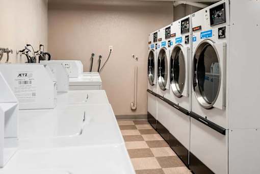A row of JETZ washing machines are lined up in a laundromat.