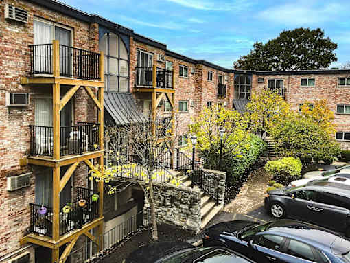 A brick building with a balcony and a tree in front.
