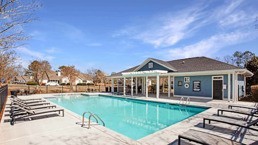 A swimming pool with sun loungers and a building in the background.