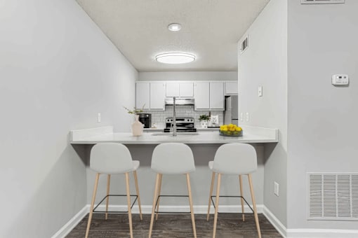 A kitchen with white chairs and a white table.
