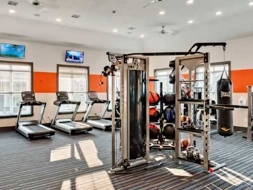 A gym with treadmills, a punching bag, and a television.